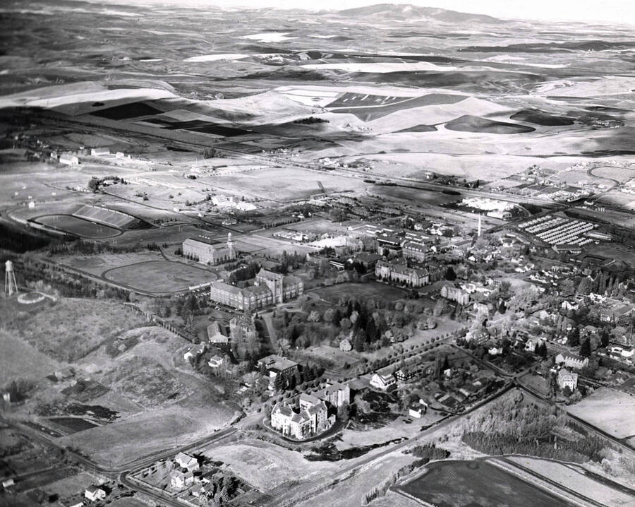 1950 photograph of University of Idaho campus. Aerial view shows both campus and the surrounding fields. Donor: Publications Dept. [PG1_003-17]