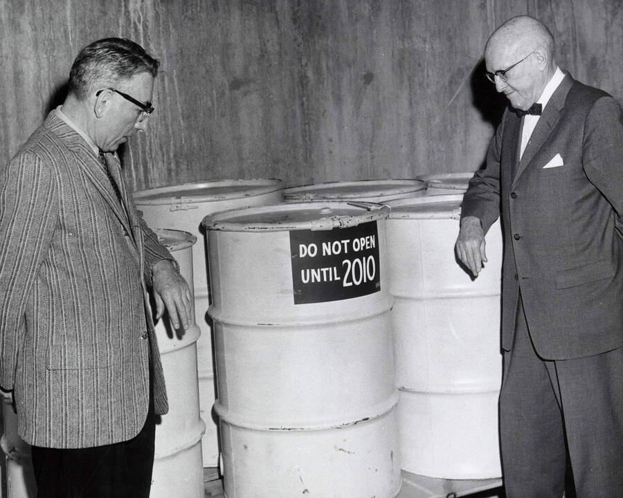 1962 photograph of Gifts. Lee Zimmerman and Donald Theophilus with W. C. Chaney's time capsule barrels. A sign labels them 'Do not open until 2010.' [PG1_400-12]