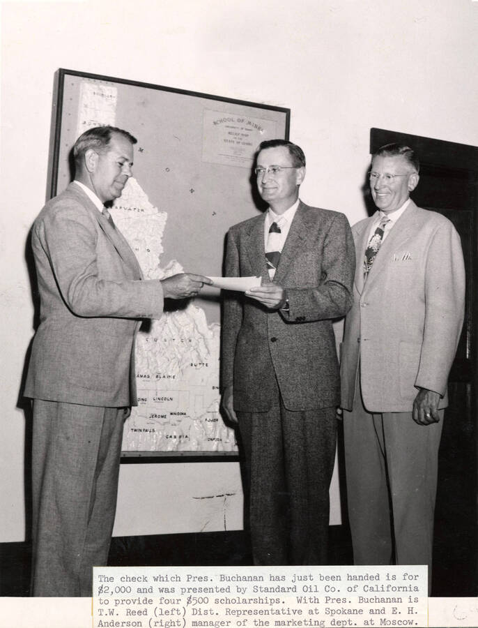 1949 photograph of Gifts. T. W. Reed presents a scholarship check to President Buchanan with E. H. Anderson. Donor: Publications Dept. [PG1_400-17]