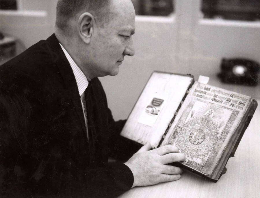 1968 photograph of Gifts. George Kellogg examines a Bible from 1518. Donor: Publications Dept. [PG1_400-18a]