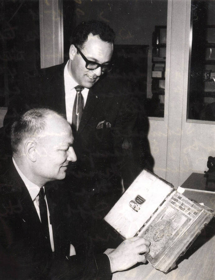1968 photograph of Gifts. George Kellogg and Richard Beck examining a bible from 1518 donated by Rev. Urban H. Schmidt. Donor: Publications Dept. [PG1_400-18b]