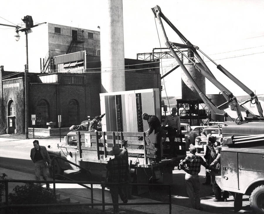 1958 photograph of Gifts. General Telephone relay switchboard being unloaded in front of the Heating Plant. Donor: Publications Dept. [PG1_400-25]