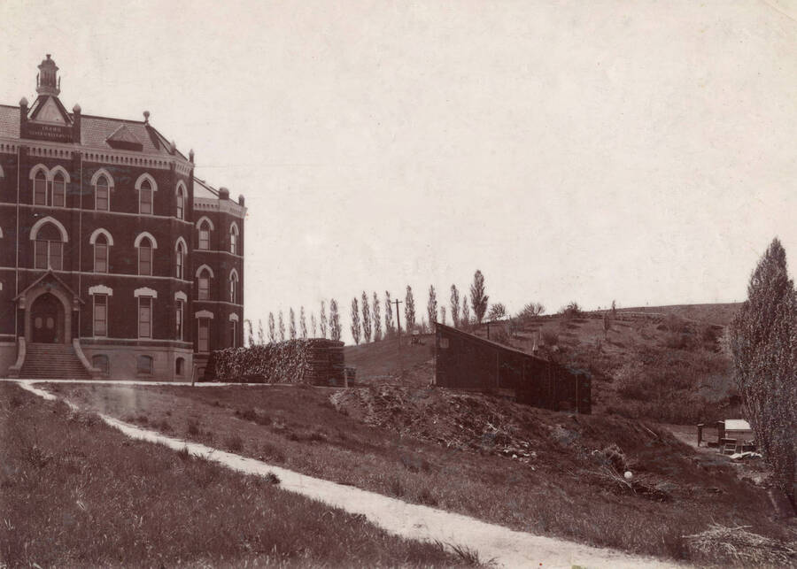 Administration Building, University of Idaho (1892-1906). Northwest corner with shed and wood-pile. [51-14]