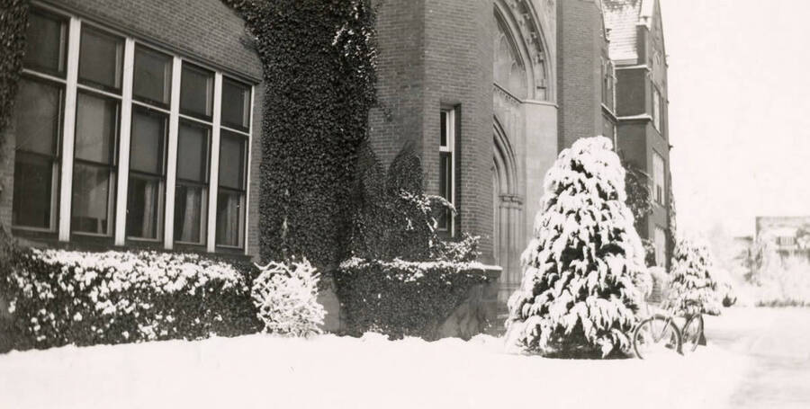1956 photograph of Administration Building. View of a bicycle parked out front in the snow. [PG1_52-144]