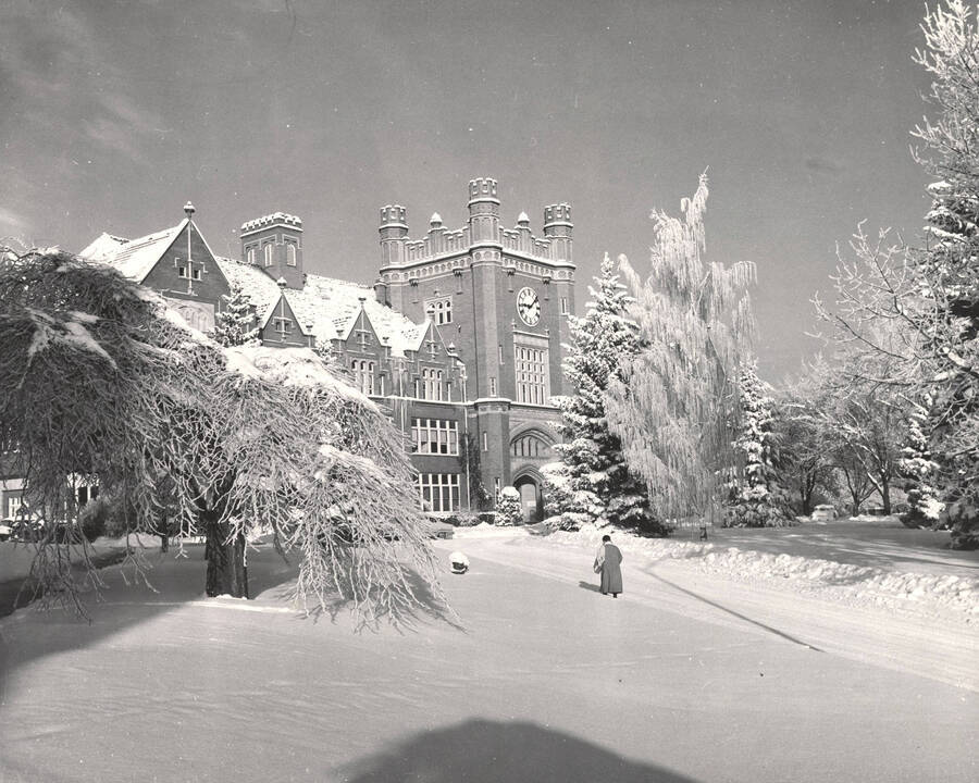 1930 photograph of Administration Building. View of winter scene with student on walkway. [PG1_52-052]