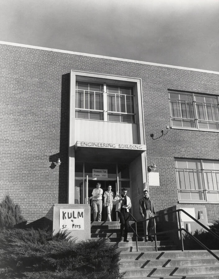 1952 photograph of Engineering Classroom Building. View of students at entrance with election poster. Donor: Publications Dept. [PG1_57-06]