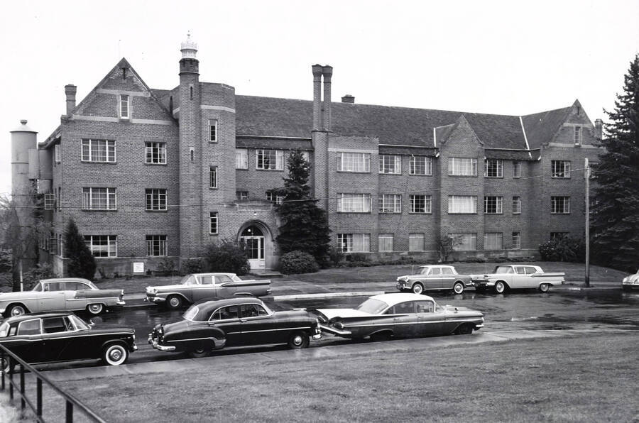 1957 photograph of Forney Hall. View of automobiles lining the street. [PG1_60-28]