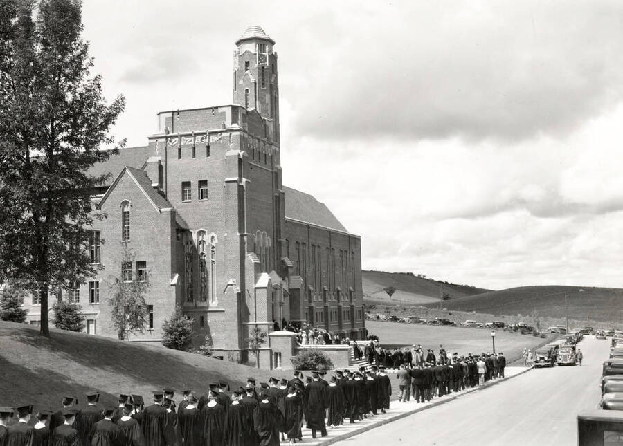 1930 photograph of Memorial Gymnasium. Graduates walk for commencements. [PG1_61-11]