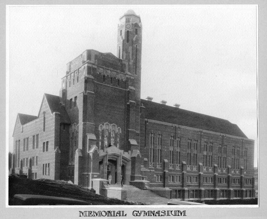 1930 photograph of Memorial Gymnasium. View of students next to building entrance. [PG1_61-17]