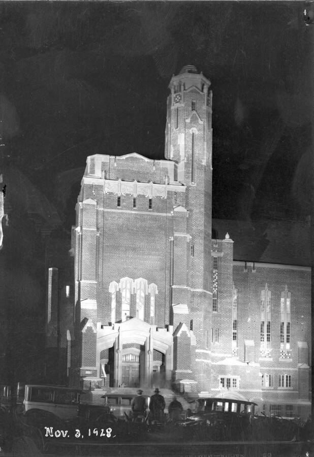 1928-11-03 photograph of Memorial Gymnasium. View of people looking at the building lit-up at night. [PG1_61-35]