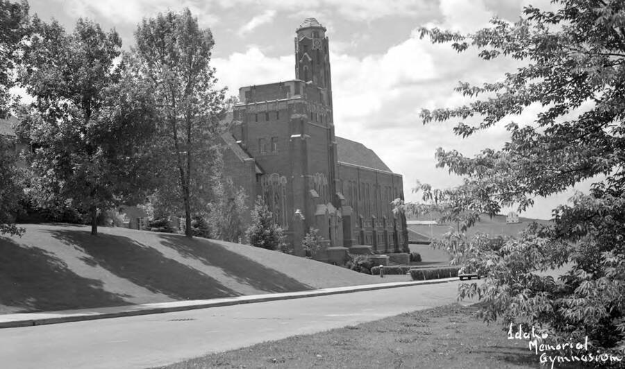 1940 photograph of Memorial Gymnasium. View framed by trees. [PG1_61-39]