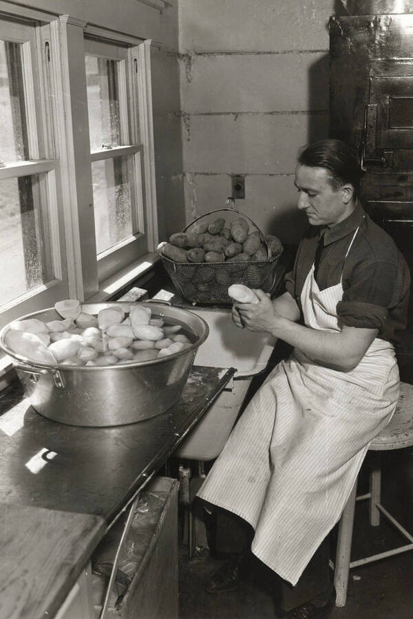 Lindley Hall, University of Idaho. Kitchen. Leonard Arrington peeling potatoes. [62-12]