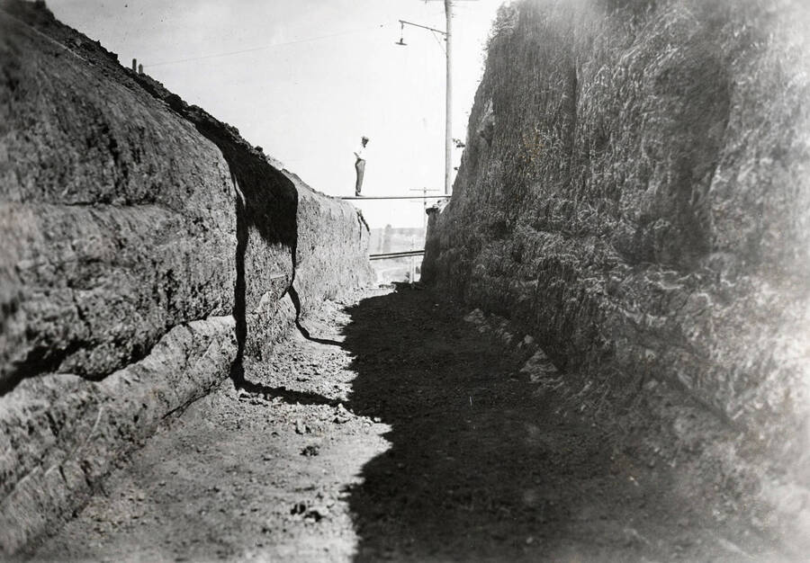 1927 photograph of Excavation for main steam tunnel. View of a man on a board spanning the tunnel. [PG1_070-03]