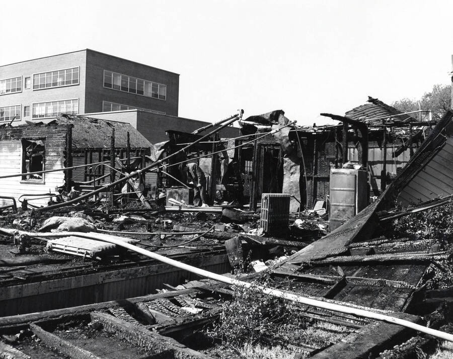 1958 photograph of Campus Club. Man studies the fire debris. [PG1_072-06]