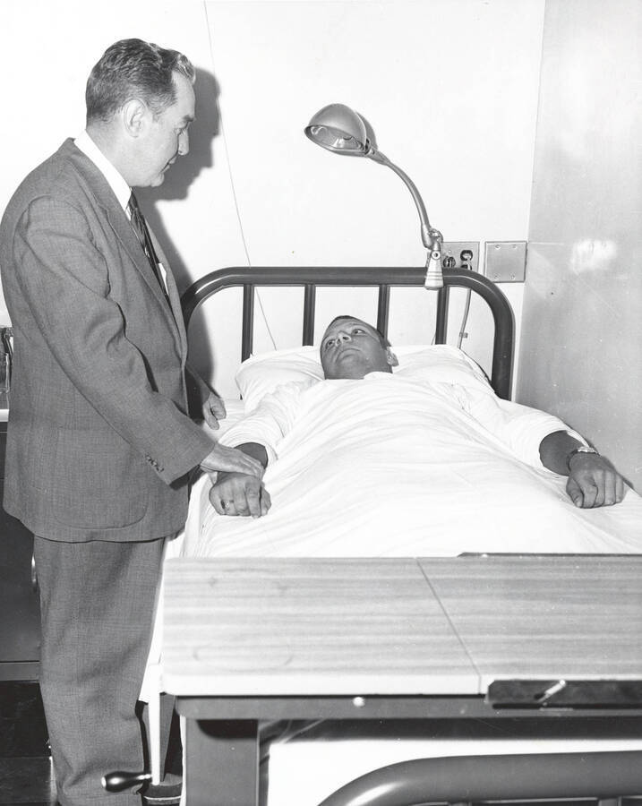 1960 photograph of Infirmary. Doctor sees to his patient. Donor: Publications Dept. [PG1_074-26]