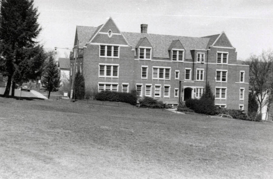1954 photograph of Infirmary. View from across the lawn, automobiles on the streets. [PG1_074-38]