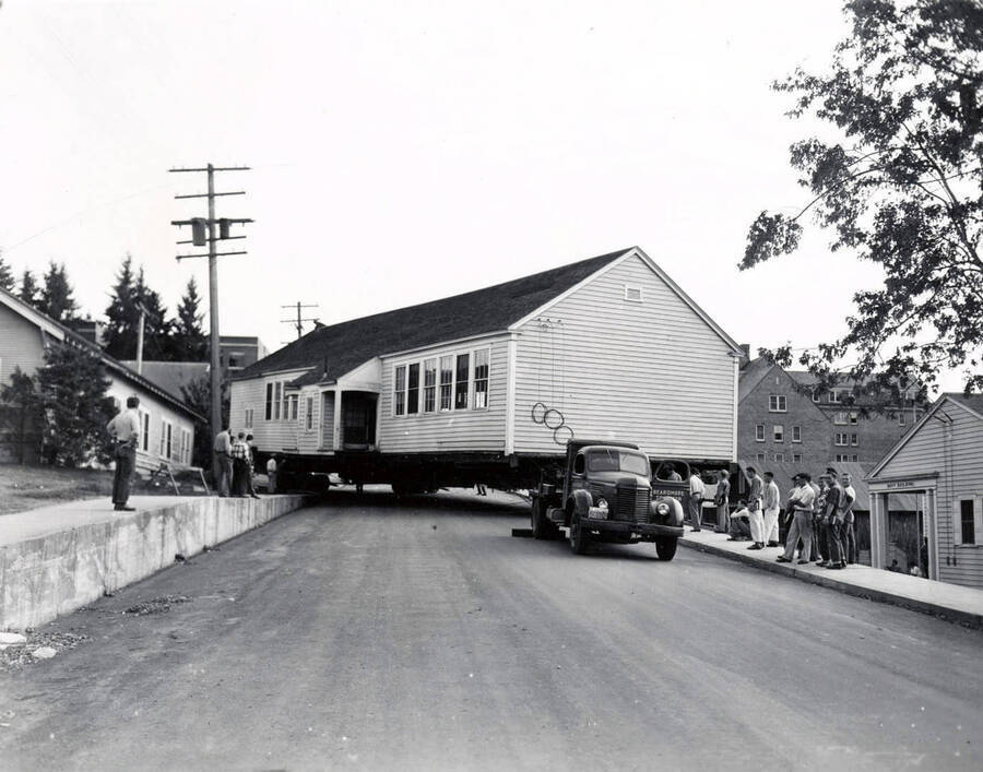 1941 photograph of Forestry Laboratory. Truck moves the building while students watch from the sidewalk. [PG1_078-02]