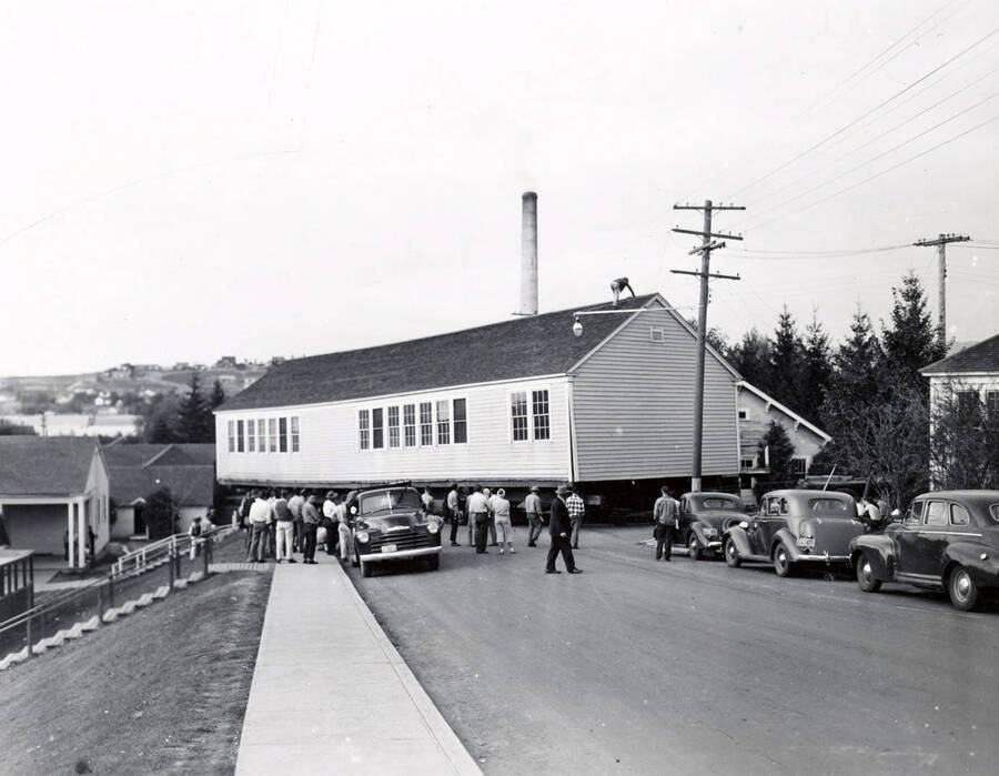 1941 photograph of Forestry Laboratory. Truck moves the building while students watch from the sidewalk. [PG1_078-03]