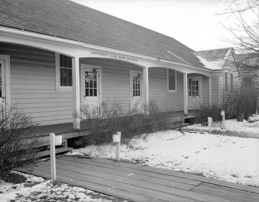 1940 photograph of University Classroom Building. Winter scene of snow covered lawns and wooden sidewalks. [PG1_082-5]