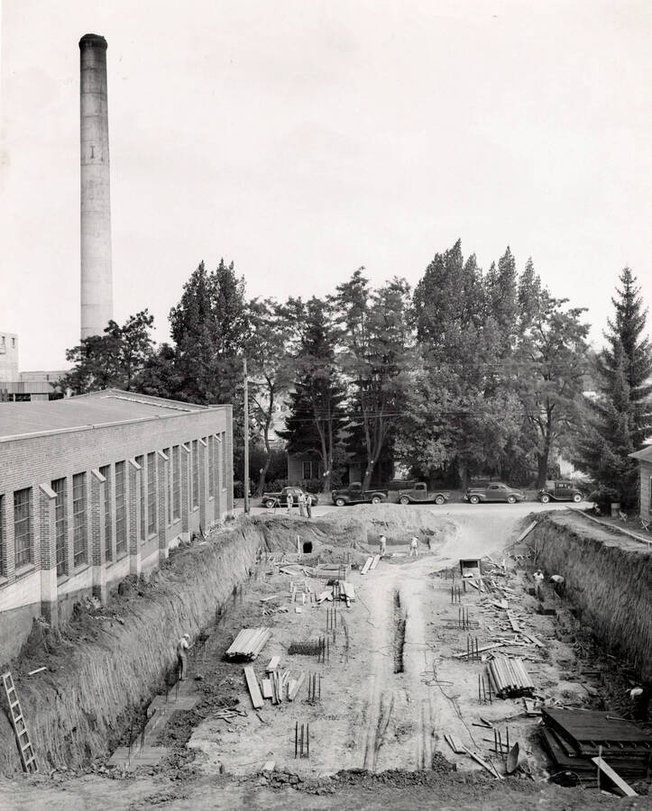 1949 photograph of Kirtley Engineering Laboratory. Workers work at the site, power plant stack on the left. [PG1_084-09]