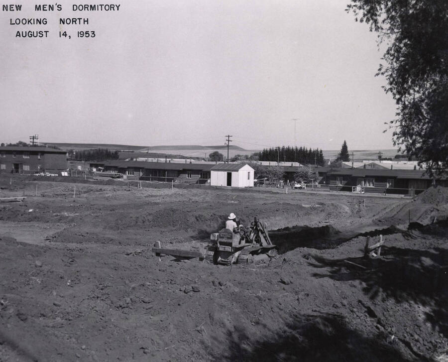 August 14, 1953 photograph of Gault Hall under construction. Construction worker in foreground. [PG1_095-08a]