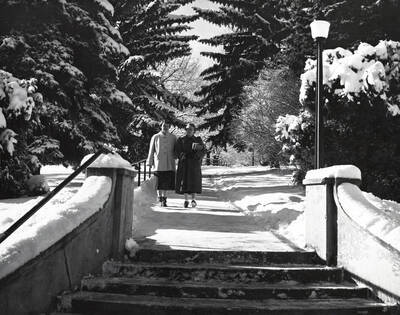 1946 photograph of the Hello Walk steps. Two students approach the steps on a snowy day. Donor: Publications Dept..