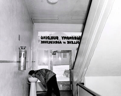 1945 photograph of Agronomy Building. A student is drinking out of a water fountain.