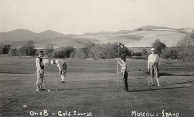1938 photograph of the Golf Course. Three adults and a child play are shown playing golf.
