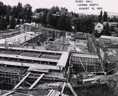 August 15, 1950 photograph of the Music Building under construction. Kappa Sigma house in the background.