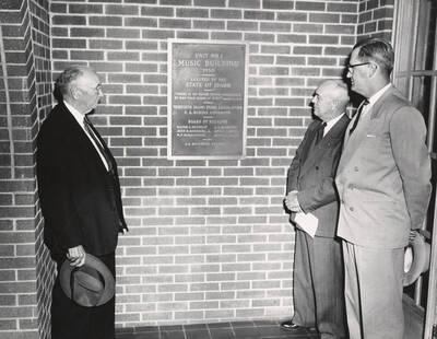 1952 photograph of men standing in front of a plaque in the Music Building. Left to right: Regent W.F. McNaughton, Governor C. A. Robins, President J.E. Buchanan. Donor: Publications Dept.
