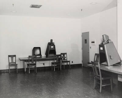1957 photograph of the Library. Microfilm reading room with several microform machines.