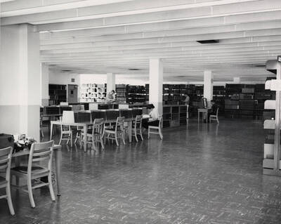 1957 photograph of the Library. Reference area with students in background.