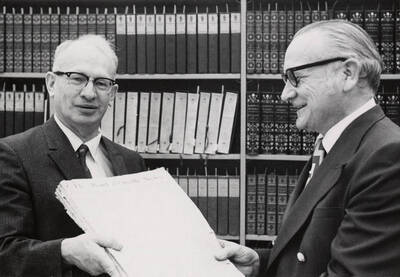 1971 photograph of the Library. Merle Wells and Charles Webbert browse the Pend d'Oreille News in the Special Collections department. Donor: News Bureau.