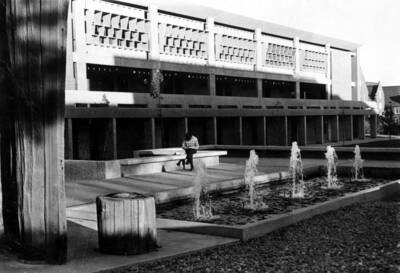 1970 photograph of the University Classroom Center. A student reads in front of a fountain.