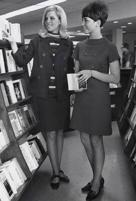 1966 photograph of the University Bookstore. Two female students browse books.