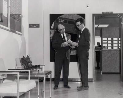 1968 photograph of the Buchanan Engineering Laboratory. Gill Corey and unidentified look over magazines. Donor: Publications Dept.
