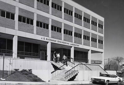1968 photograph of the Buchanan Engineering Laboratory. Students and an automobile in foreground. Donor: Publications Dept.