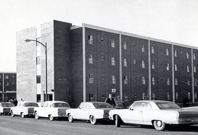 1970 photograph of the Wallace Residence Center. Students and automobiles in foreground.