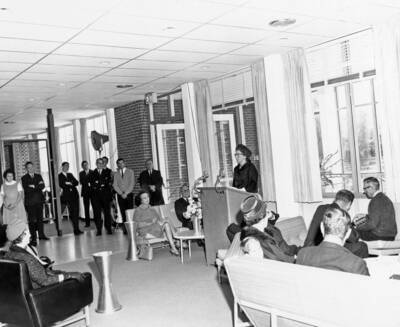 1963 photograph of the Wallace Residence Center dedication ceremony. Woman stands at lectern. Donor: Publications Dept.