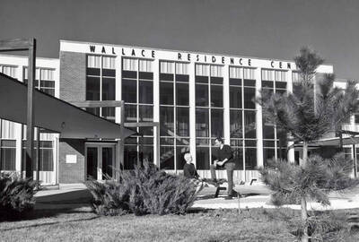 1969 photograph of the Wallace Residence Center. Two students talk before the entrance. Donor: Publications Dept.