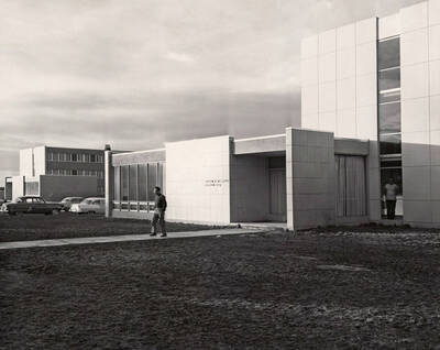 1957 photograph of the William J. McConnell Residence Hall. Student in foreground, automobiles in background. Donor: Publications Dept.
