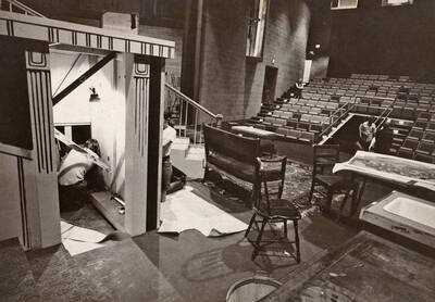 1975 photograph of Hartung Theatre. Students build the set on stage.
