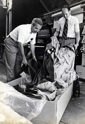 1974 photograph of the interior of the Hartung Theatre. Ed Chavez and unidentified unpack curtains.