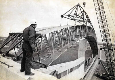 1975 photograph of the Kibbie-ASUI Activity Center under construction. Construction worker in foreground.