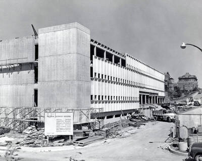 1963 photograph of Renfrew Hall (Physical Science Building) under construction. Automobiles in foreground and background. Donor: Publications Dept.