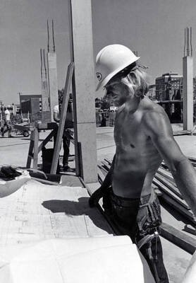 1974 photograph of Menard Law Building under construction. A shirtless man in foreground.