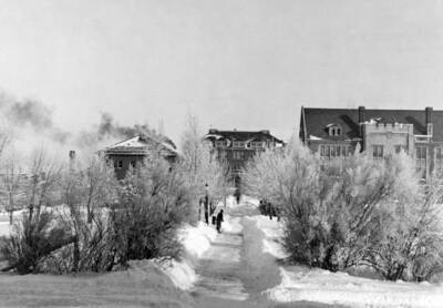 1937 panoramic photograph of University of Idaho campus. Worker is shoveling snow from campus sidewalks.