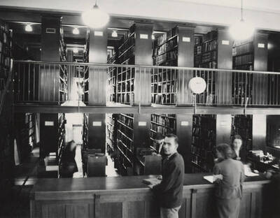 1937 photograph of the Library. Library employees assist students at the loan desk.