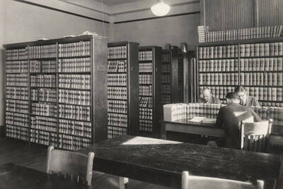 1936 photograph of the Law Library. Students study around stacks of law books.
