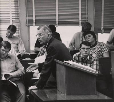 1965 photograph of the College of Law. Students take notes during a lecture.